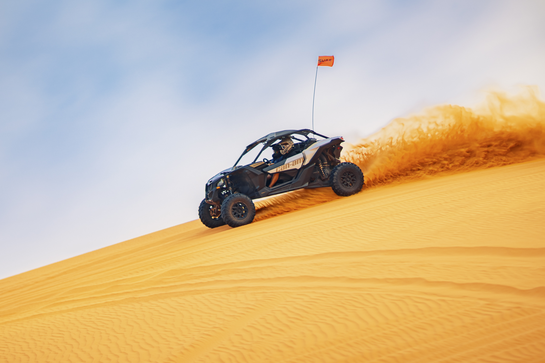 Off-road UTV climbing Sand Hollow’s golden dunes, creating a sand trail in Utah’s exciting adventure terrain.