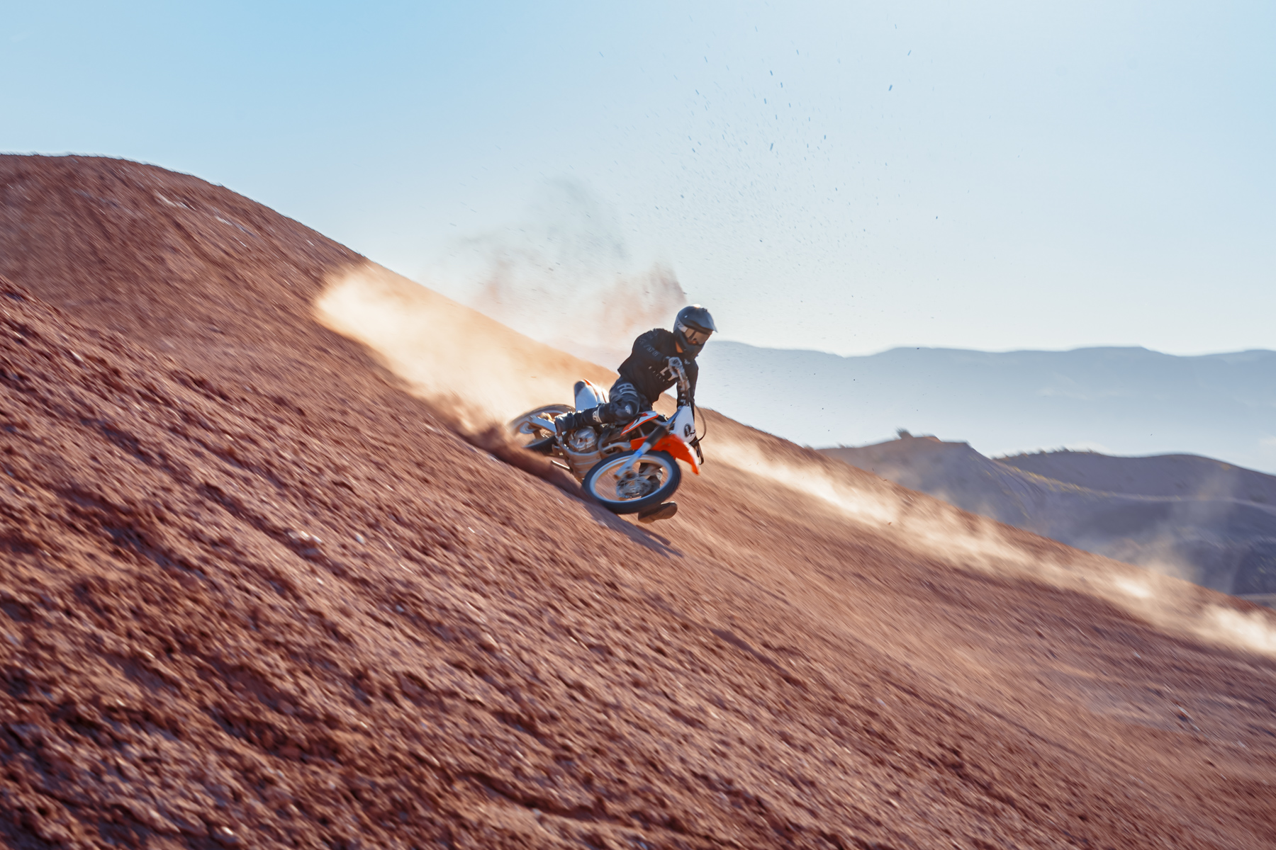 Dirt bike rider carving down a steep hill on Sand Hollow trails in Utah, near Zion and St. George, for thrilling off-road adventure.