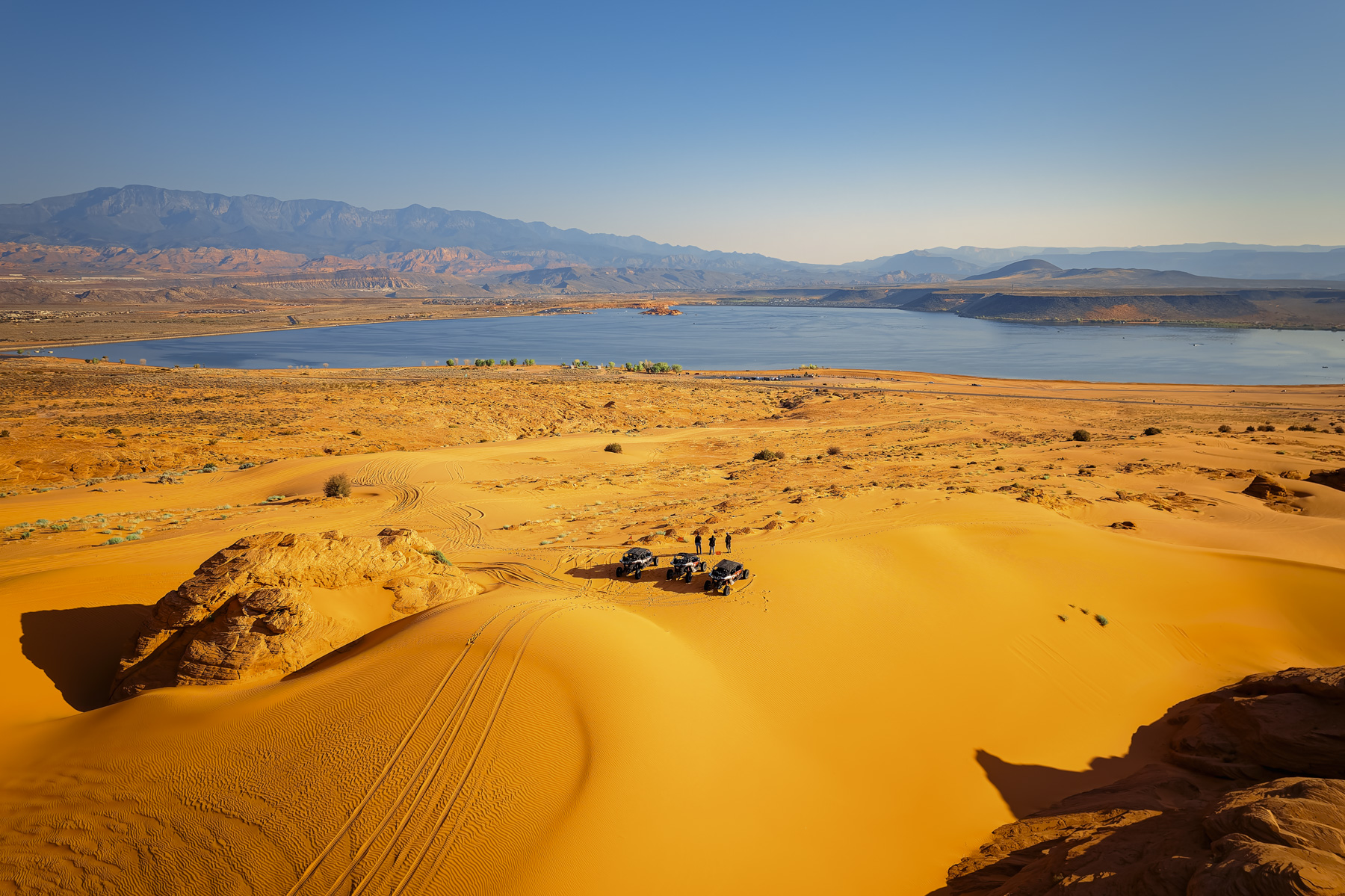 UTVs parked on Sand Hollow’s scenic sand dunes with views of the lake and mountains, perfect for off-road adventures near Zion and St. George.