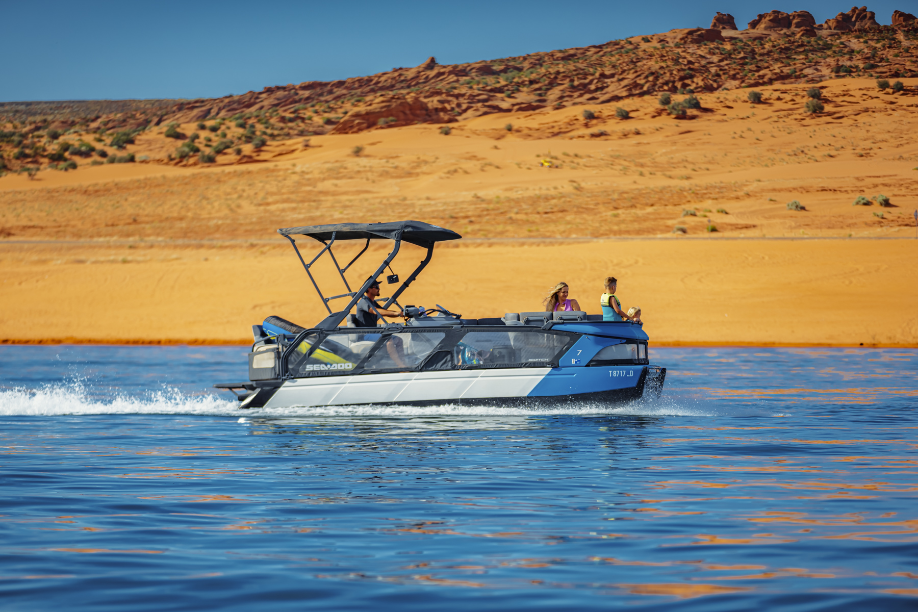 Sea-Doo Switch boat cruising on Sand Hollow Reservoir with scenic red rock backdrop, perfect for Southern Utah boat rentals and water adventures.