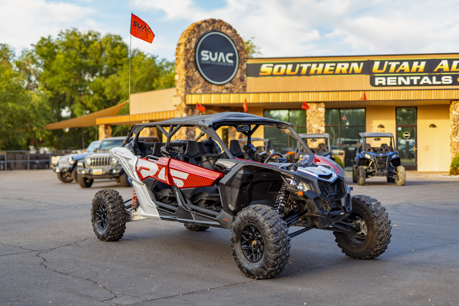 Red and white Can-Am Maverick X3 Max Turbo RS UTV parked at Southern Utah Adventure Center, ideal for off-road adventures near Sand Hollow and Zion National Park.